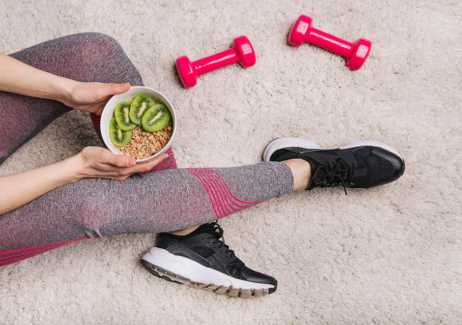 Desportista com uma taça de papas de aveia e kiwi um exemplo de refeição saudável após exercício físico